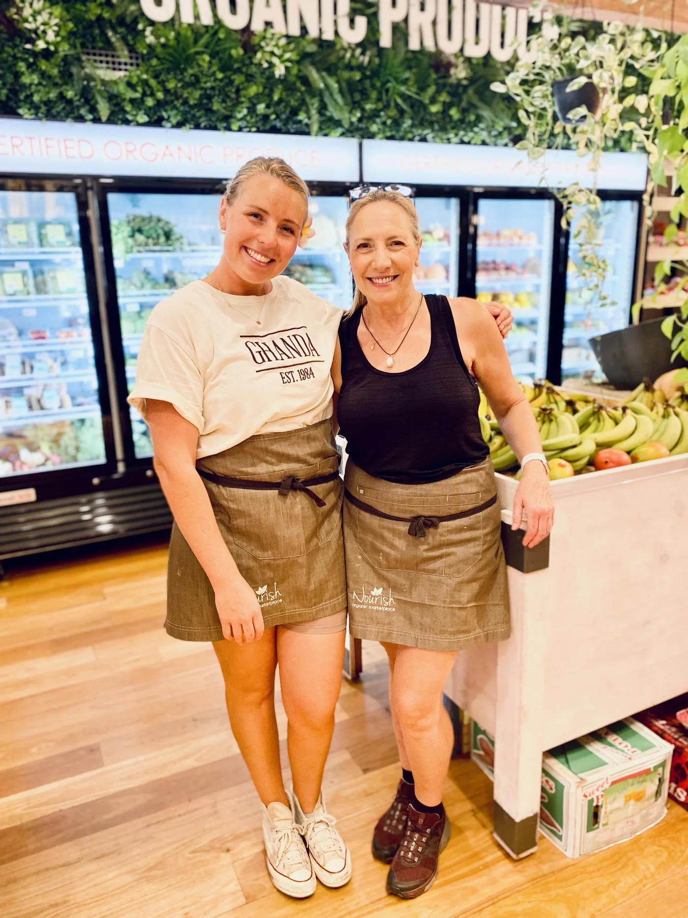 Two team members in front of the certified organic produce fridges